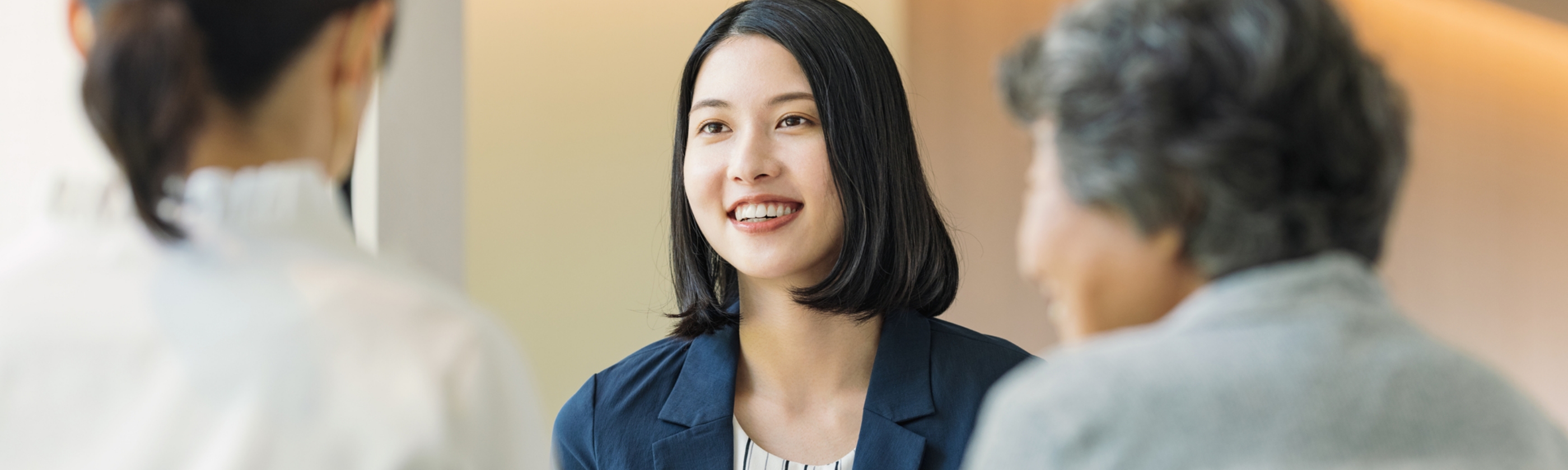 向かい合っている人に話しかけているフォーマルな服装の女性