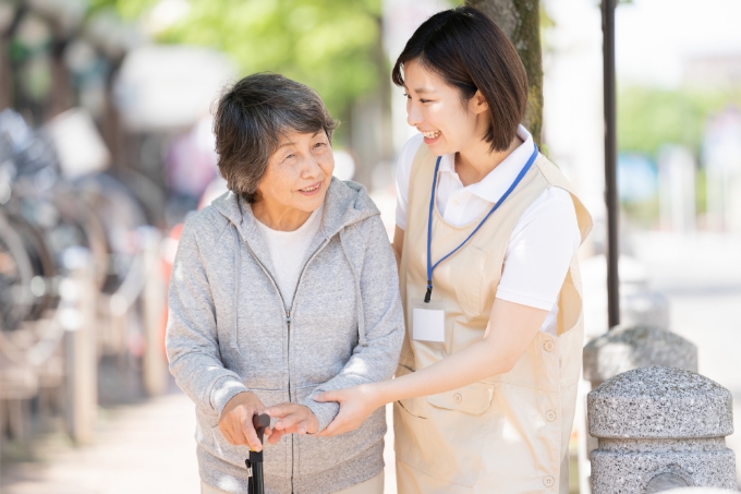 シニアの女性を支えながら一緒に歩く女性