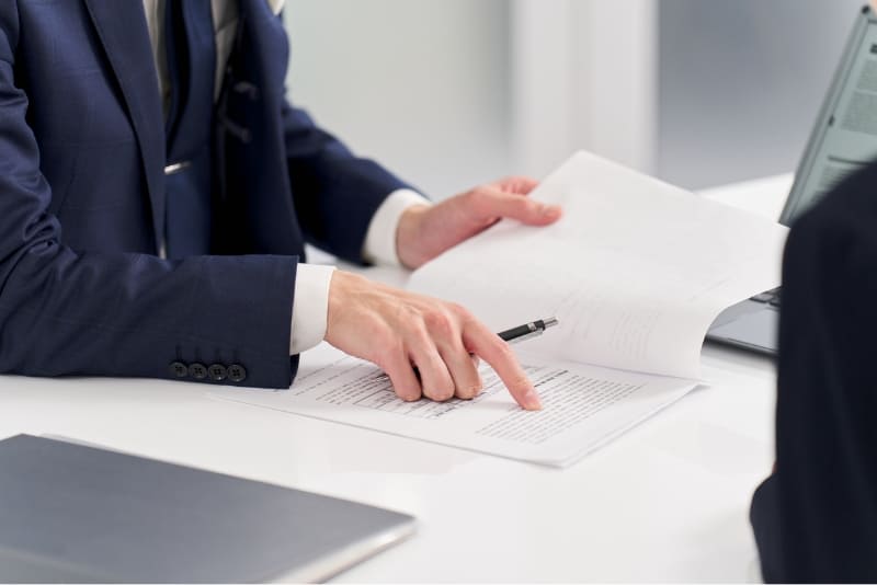 書類の一部を指さす手元