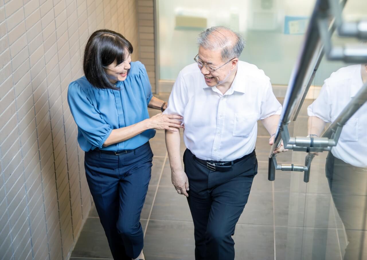 シニアの男性を支えながら一緒に歩く生活支援員の女性