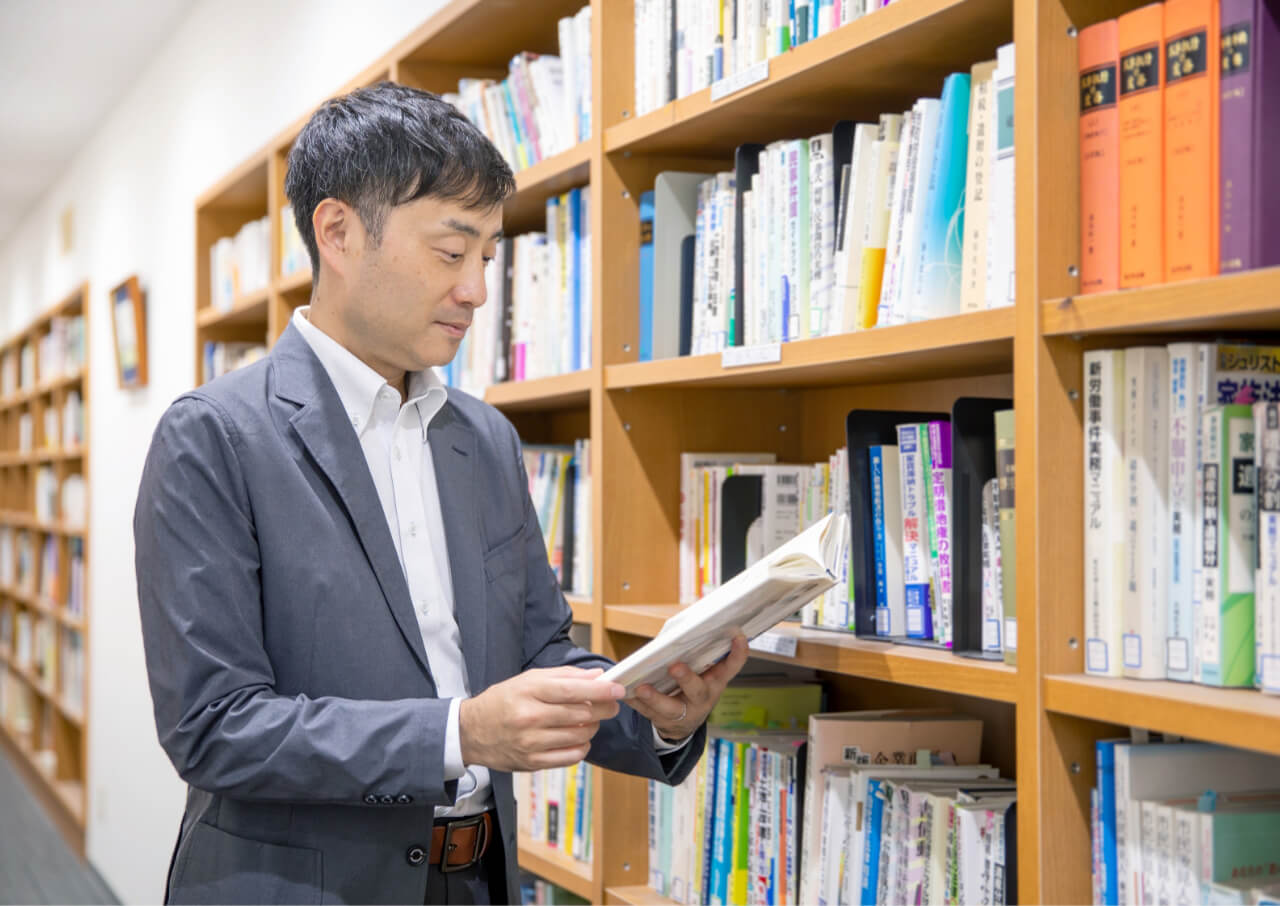 本棚の前で本を眺めている法務スタッフ