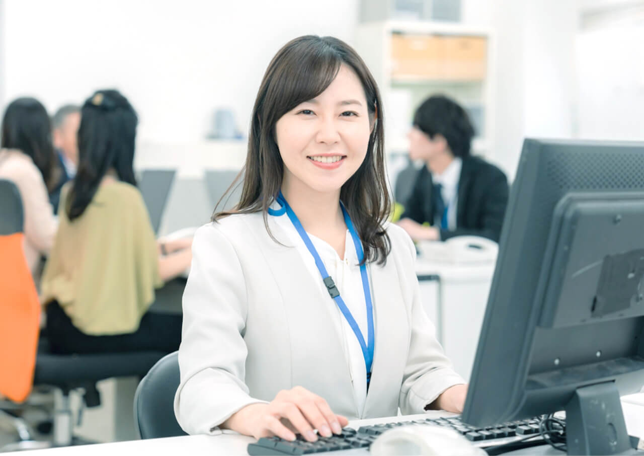 パソコンで作業をしつつ笑いかけている管理スタッフの女性