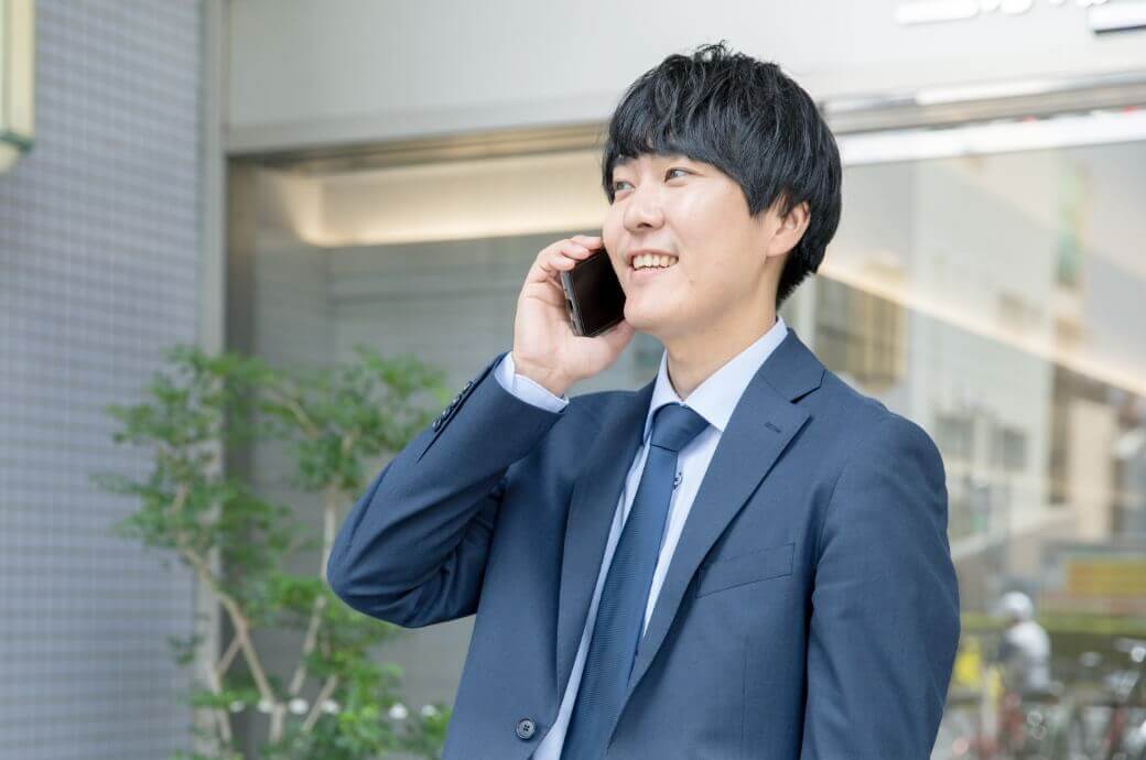 携帯で誰かと電話をしているスーツを着ている相談員の男性