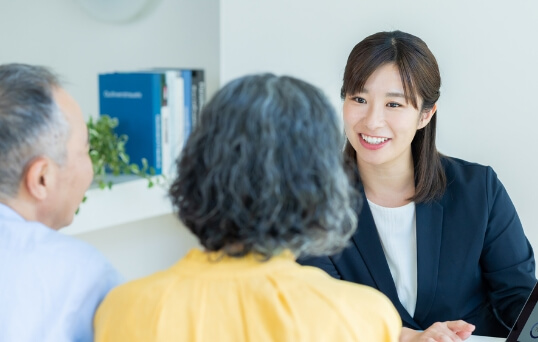 老夫婦に笑いかけるスーツ姿の女性