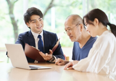 男女に話しかけるスーツ姿の男性