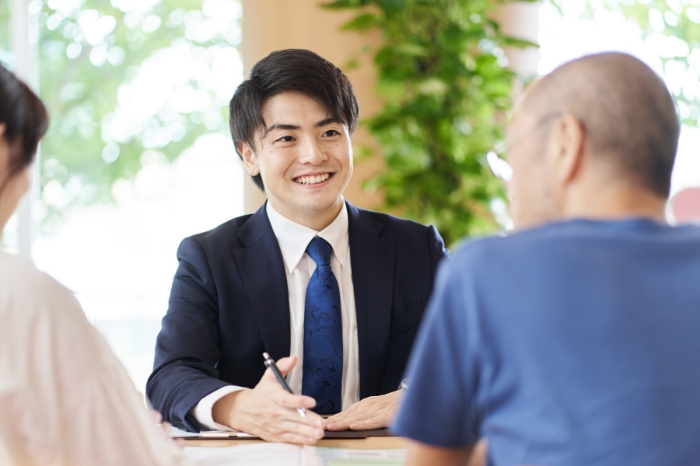 向かい側の人に笑いかけているスーツの男性