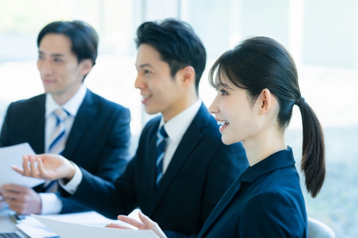 誰かに話しかけているスーツ姿の男女3人