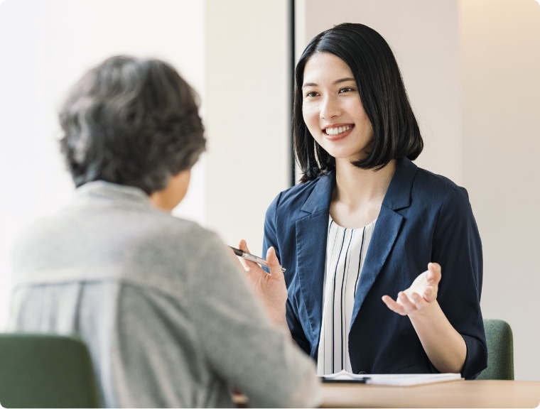 シニアの女性に微笑みかけるスーツ姿の女性
