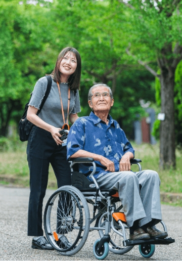 車椅子に乗っている男性と、それを押している女性