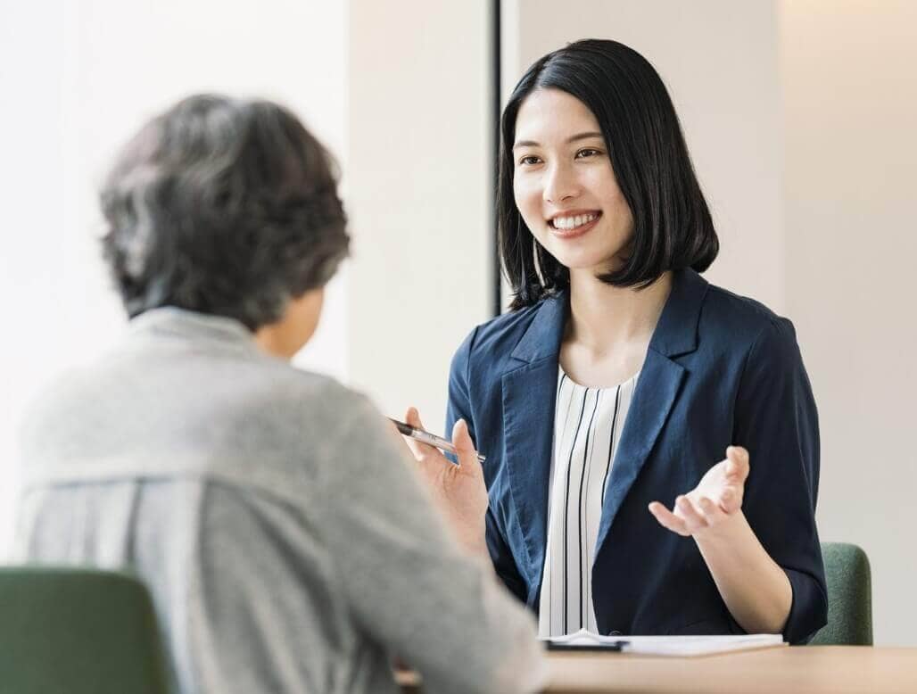 シニアの女性に微笑みかけるスーツ姿の女性